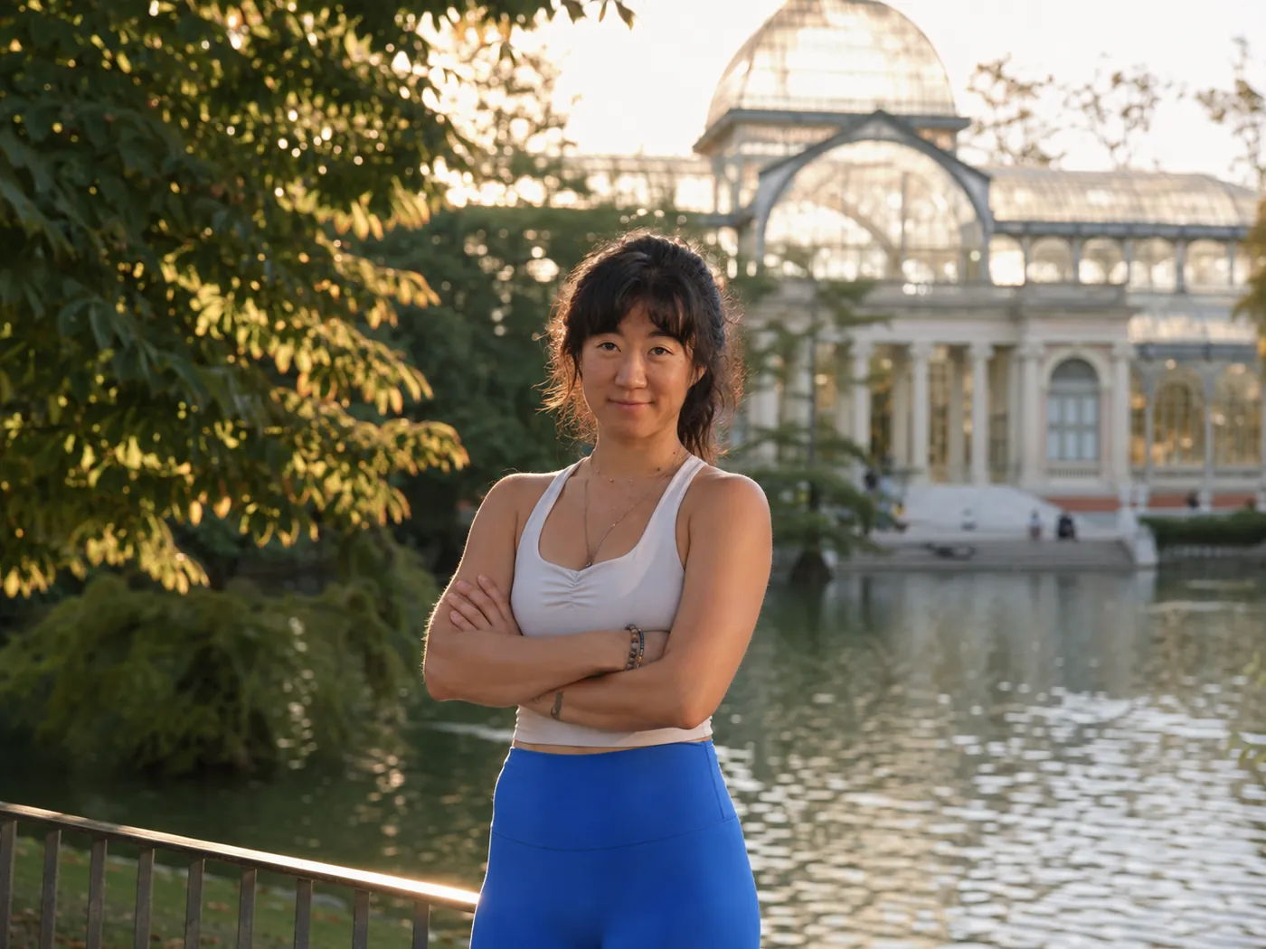 Julie, private personal trainer, standing confidently by the Crystal Palace in Retiro Park