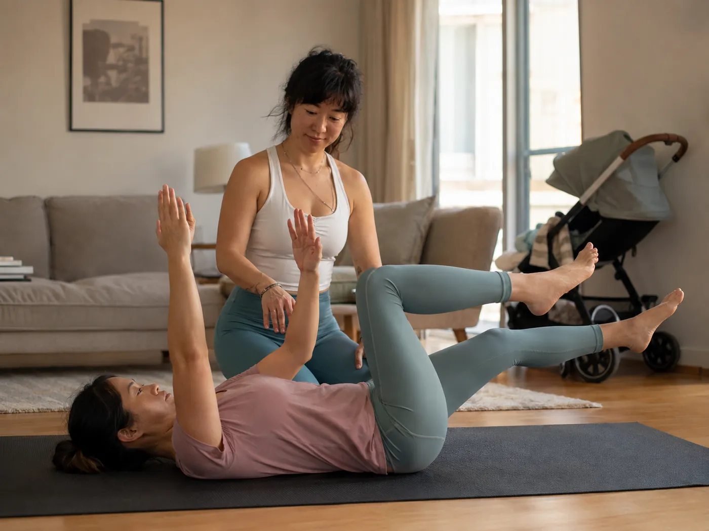 Julie guiding a postpartum client through a gentle bridge exercise at home