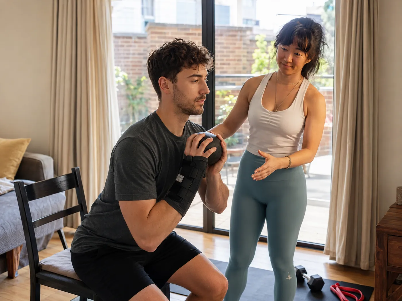 Julie guiding a client through a mobility exercise with a wrist brace