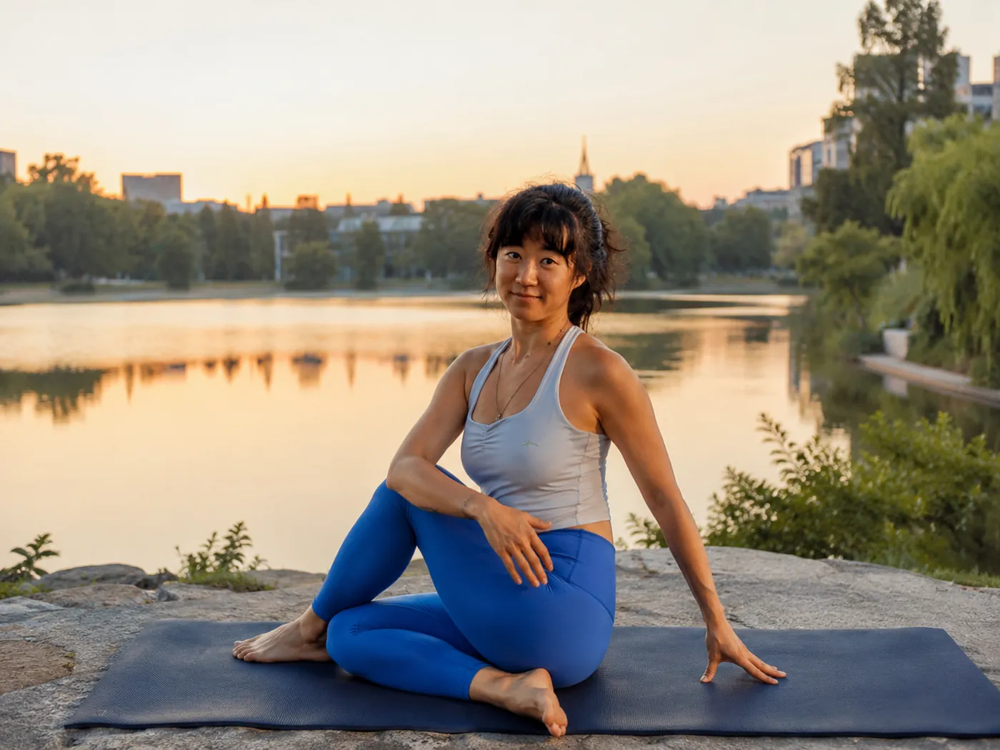 Julie sitting on a mat by a lake in Madrid at sunset